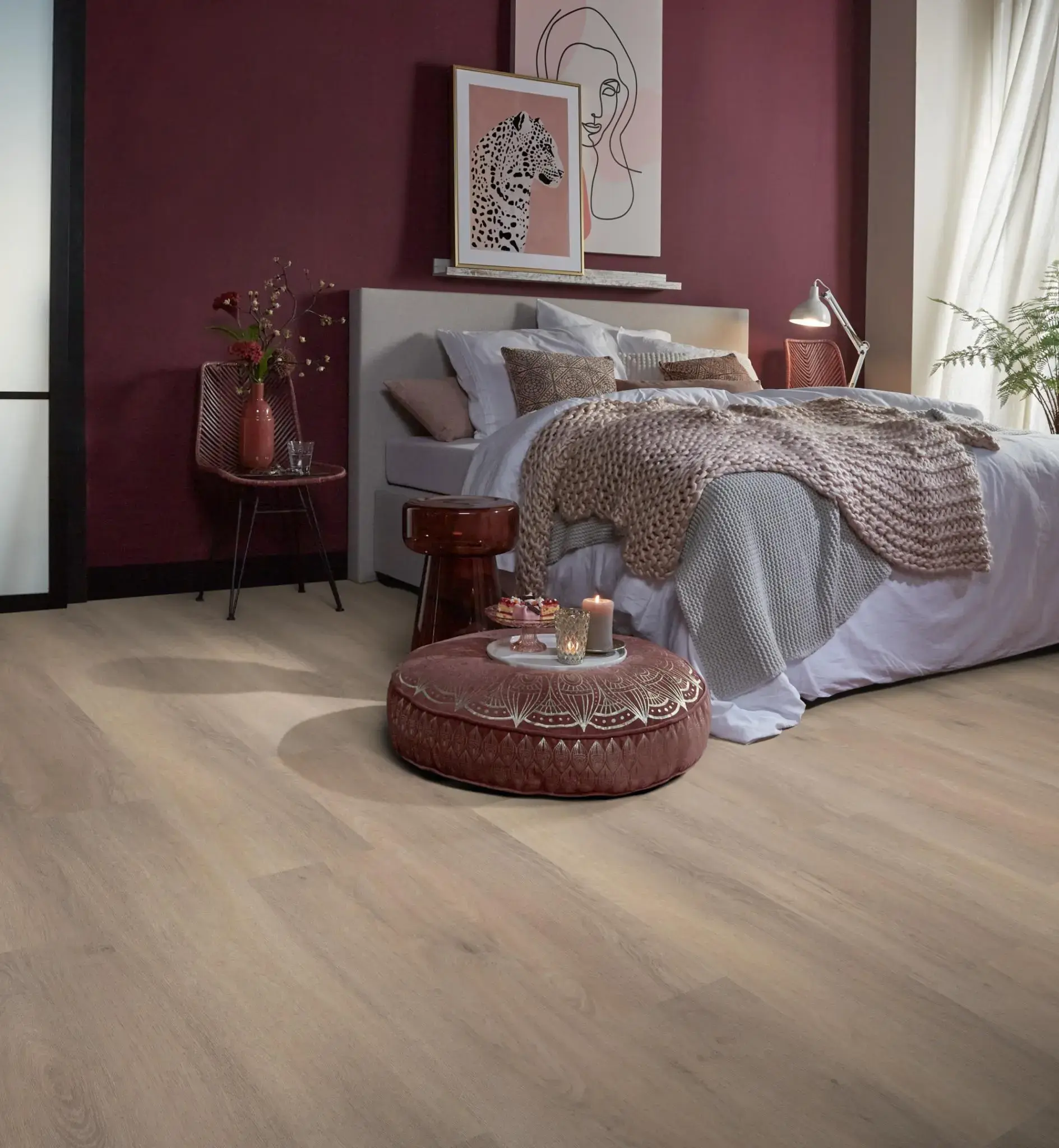Slaapkamer met houten vloer, bordeauxrode wand en opgemaakt bed