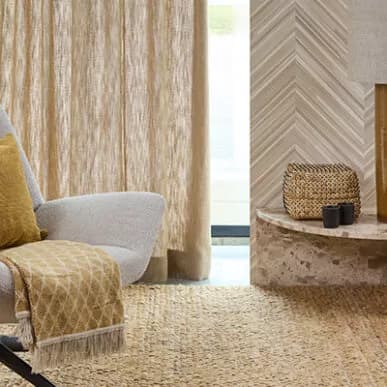 Woonkamer met linnen gordijnen, fauteuil en jute vloerkleed